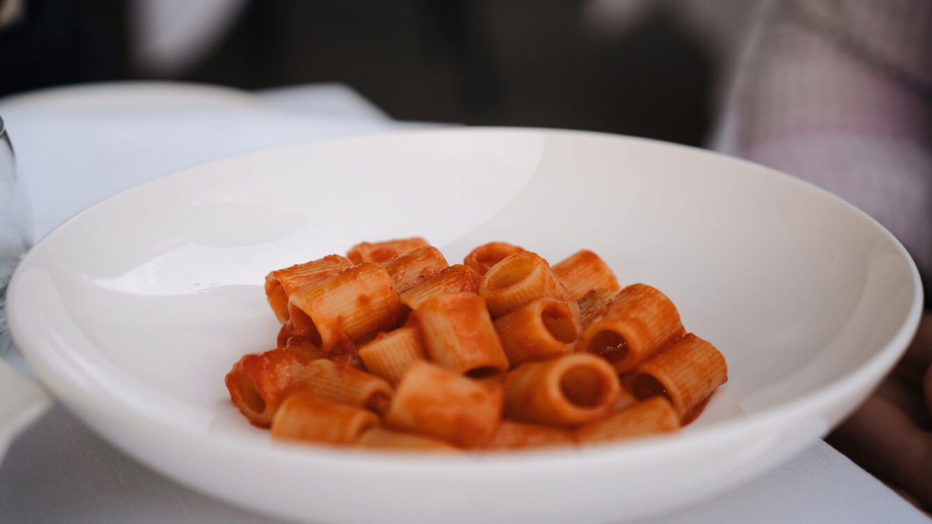 Harry's Bistrò (c) Julia Riedesser | 1000things Teller mit klassischer italienischer Rigatoni Pasta in fruchtiger Tomatensauce, serviert im eleganten Ambiente von Harry’s Bistrò