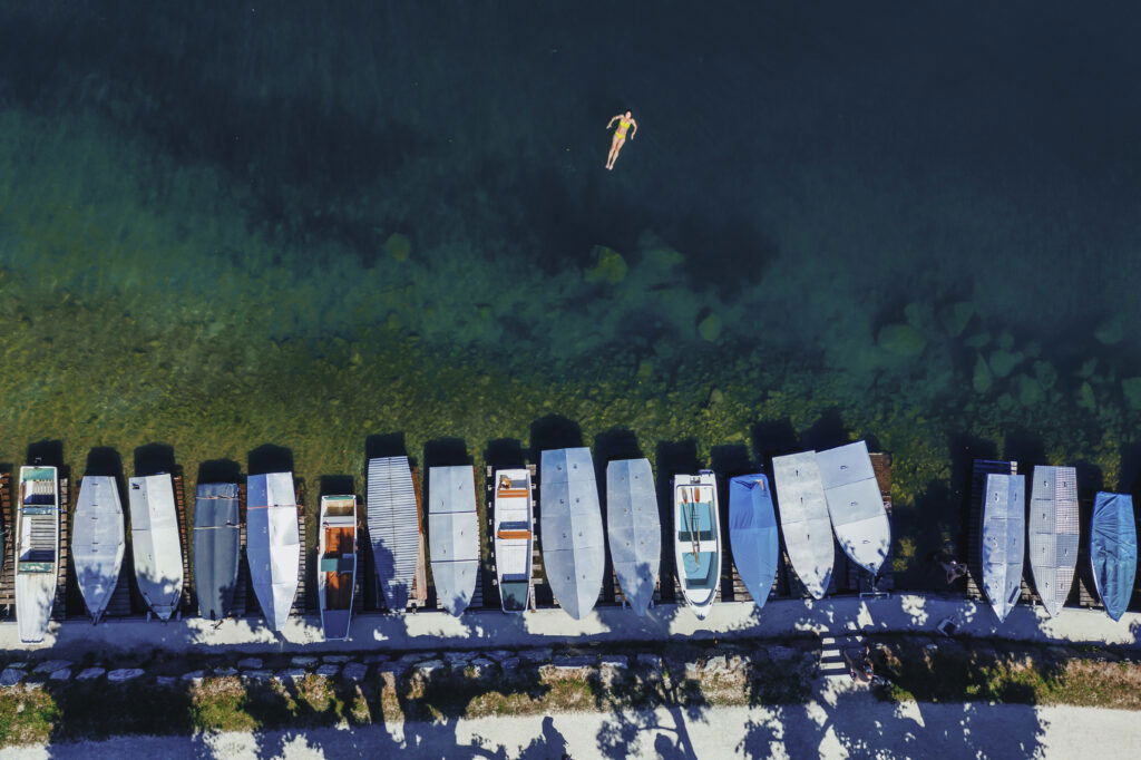 Eine Frau schwimmt im Zeller See nahe eines Bootssteges.