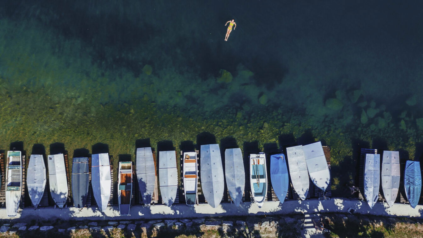 Eine Frau schwimmt im Zeller See nahe eines Bootssteges.