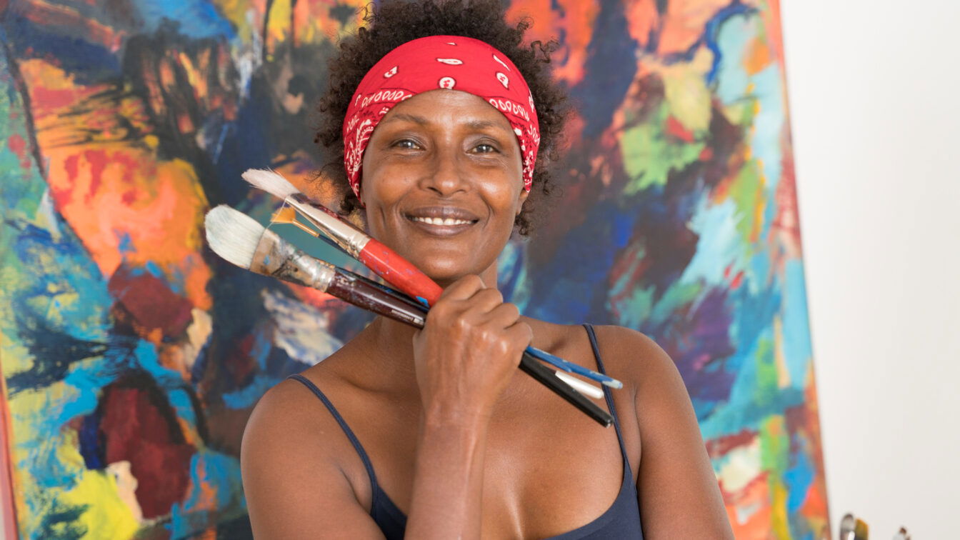 © Desert Flower Foundation Waris Dirie vor einer künstlerischen Leinwand