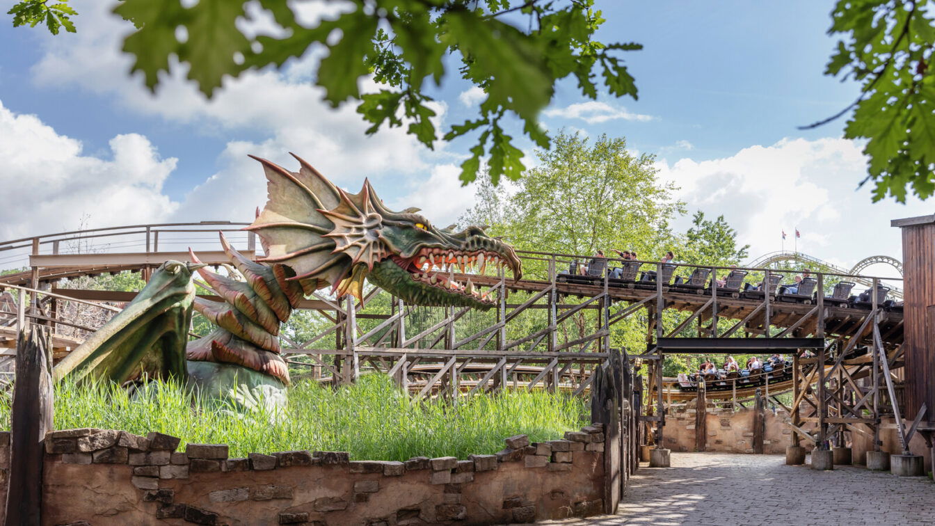 (c) Efteling Ein Drachenkopf mit Achterbahn im Hintergrund im Efteling Freizeitpark.