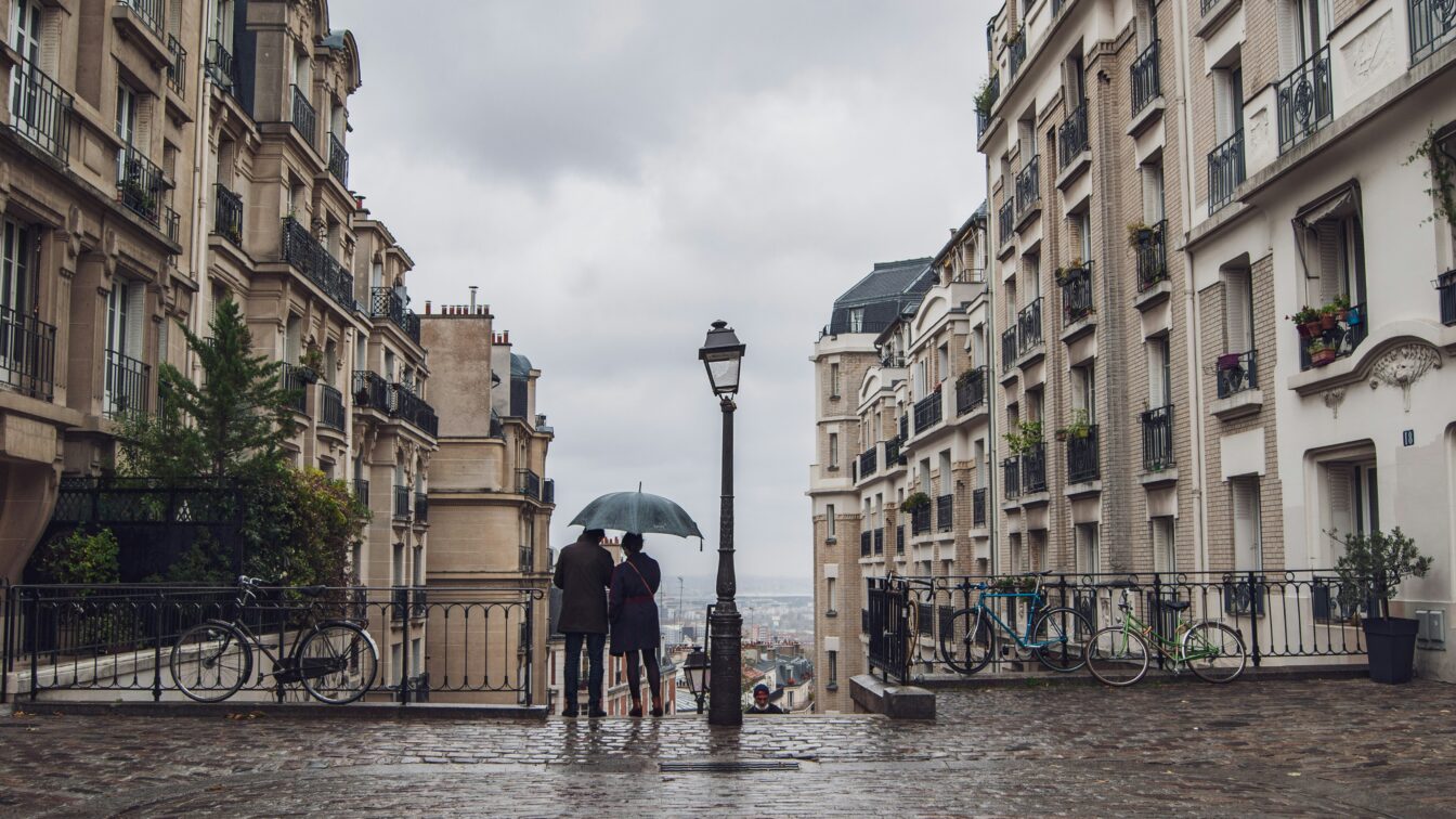 (c) Jean Baptiste | Unsplash Regen in Paris, ein Paar unterm Regenschirm von Hinten.