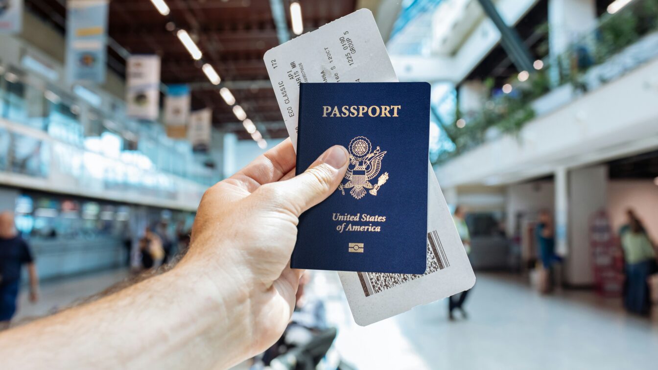 (c) Unsplash eine Hand, die Reisepass und Boarding Pass am Flughafen hält