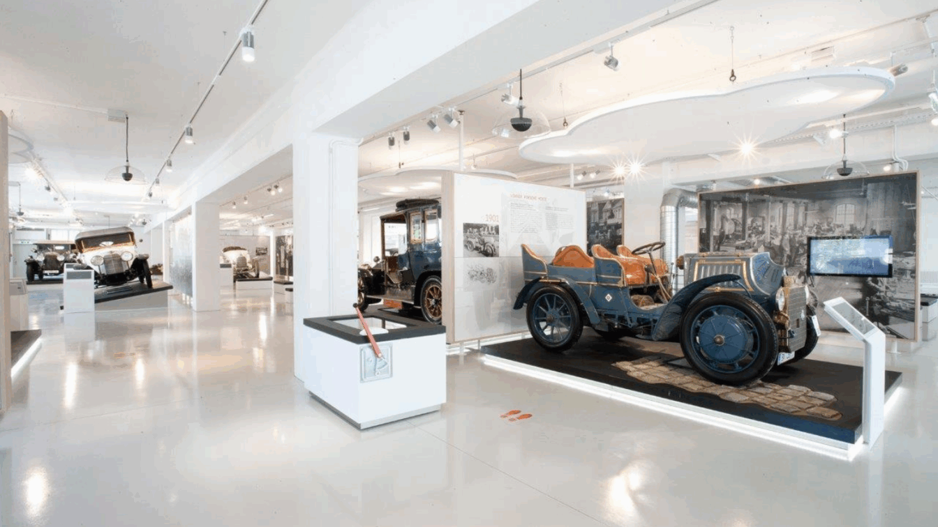 (c) ebihara photography Innenansicht des fahr(T)raum Museums mit historischen Automobilen, darunter der Lohner-Porsche Mixte von 1901, ausgestellt in moderner, heller Umgebung – ideal für Technik- und Autogeschichte-Enthusiasten.